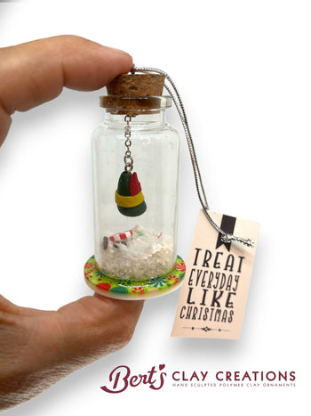 Miniature glass bottle with a decorated lid, small figurine, and 'Treat Everyday Like Christmas' tag held by a hand.